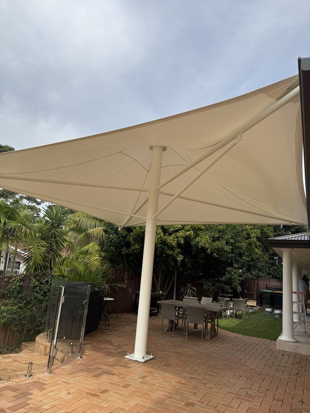 Large cream umbrella canopy on a single post shading a brick paved courtyard and dining setting., Alfords Point