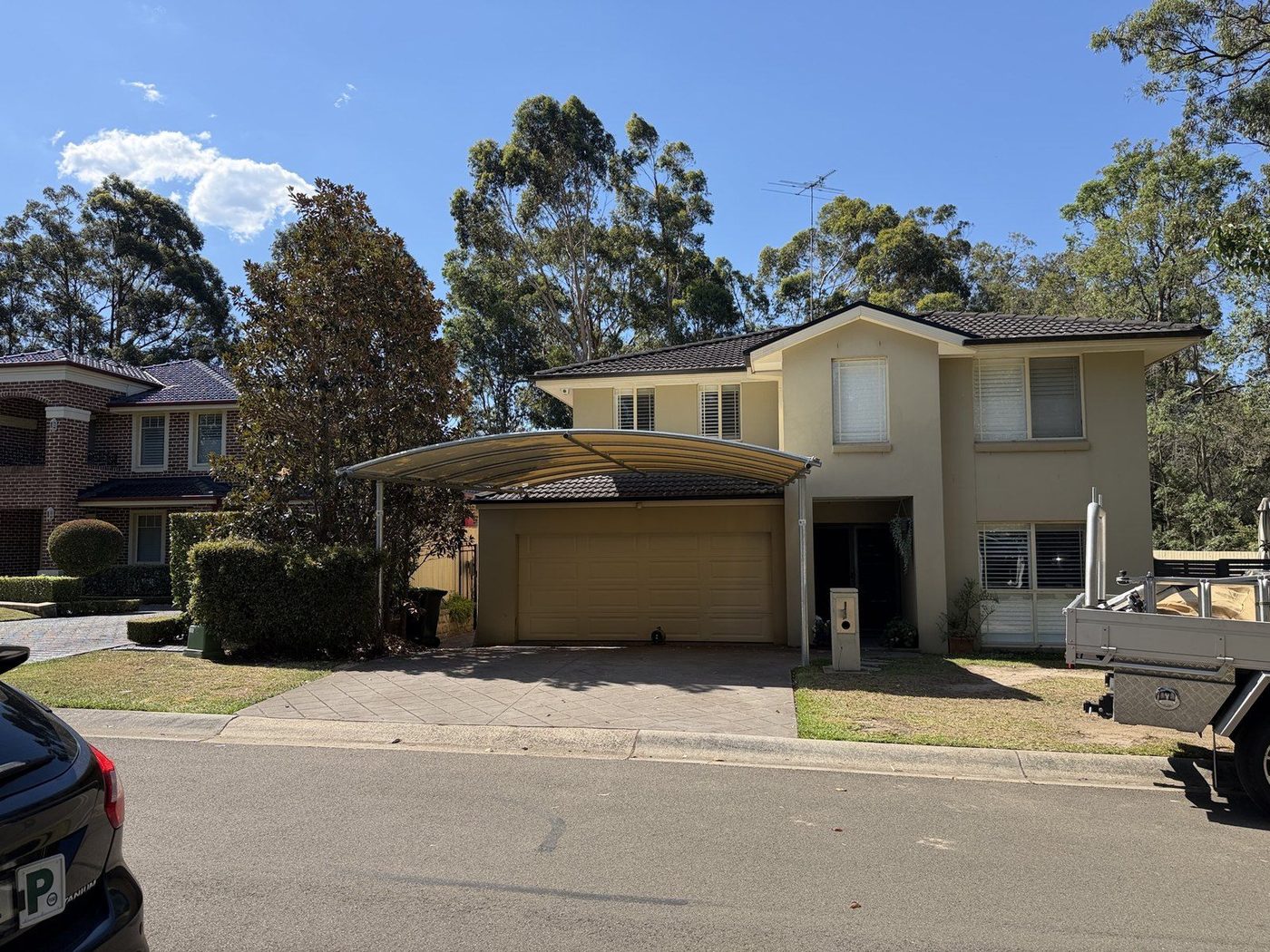 A curved cream canopy on steel posts shades the driveway in front of a two-storey home., Beaumont Hills
