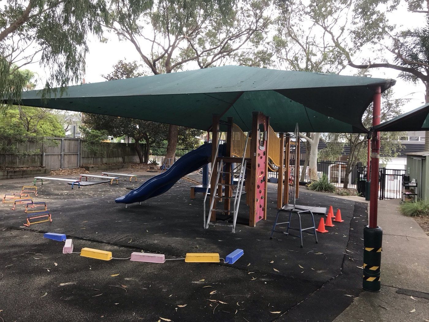 Green shade sail over a school playground with a slide, climbing frame and rubber softfall., Freshwater