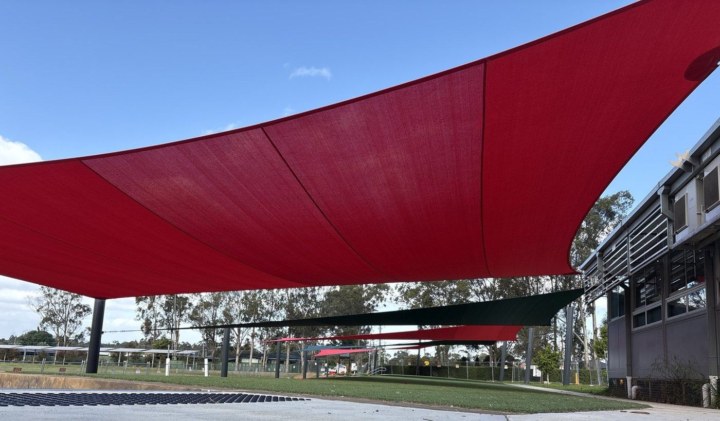 Large red shade sails over an open school ground, with dark green and red sails beyond., Winmalee